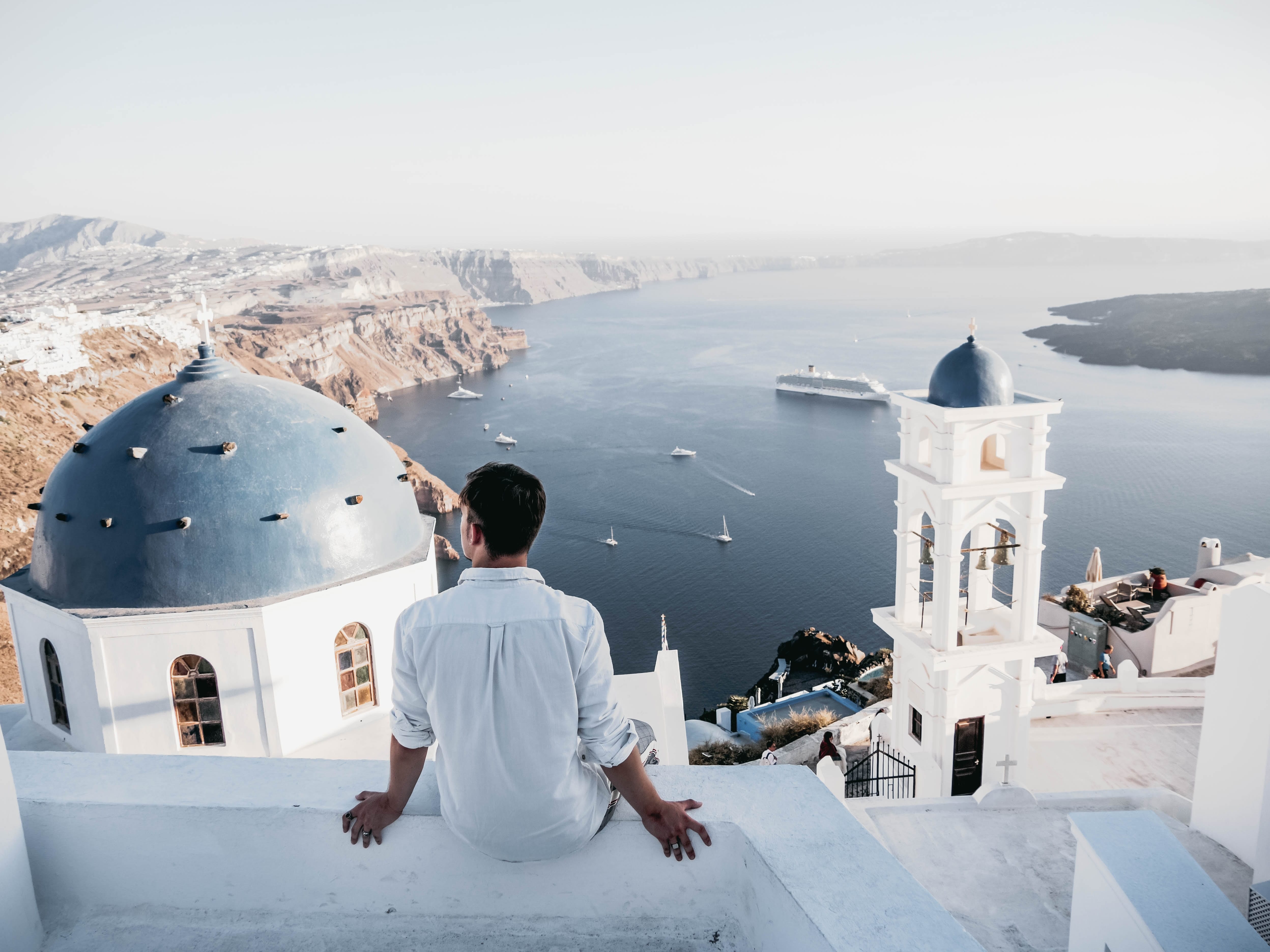 greece - man sitting on edge looking over water